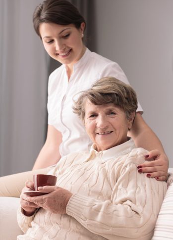 Young female caregiver taking care of older woman